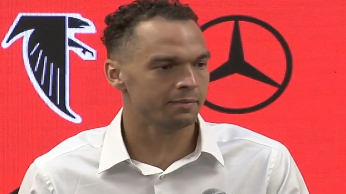 Desmond Ridder, Falcons QB, stands against a backdrop with the team logo and the Mercedes-Benz logo